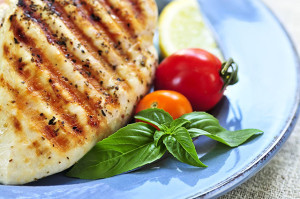 Grilled chicken breasts on a plate with fresh vegetables
